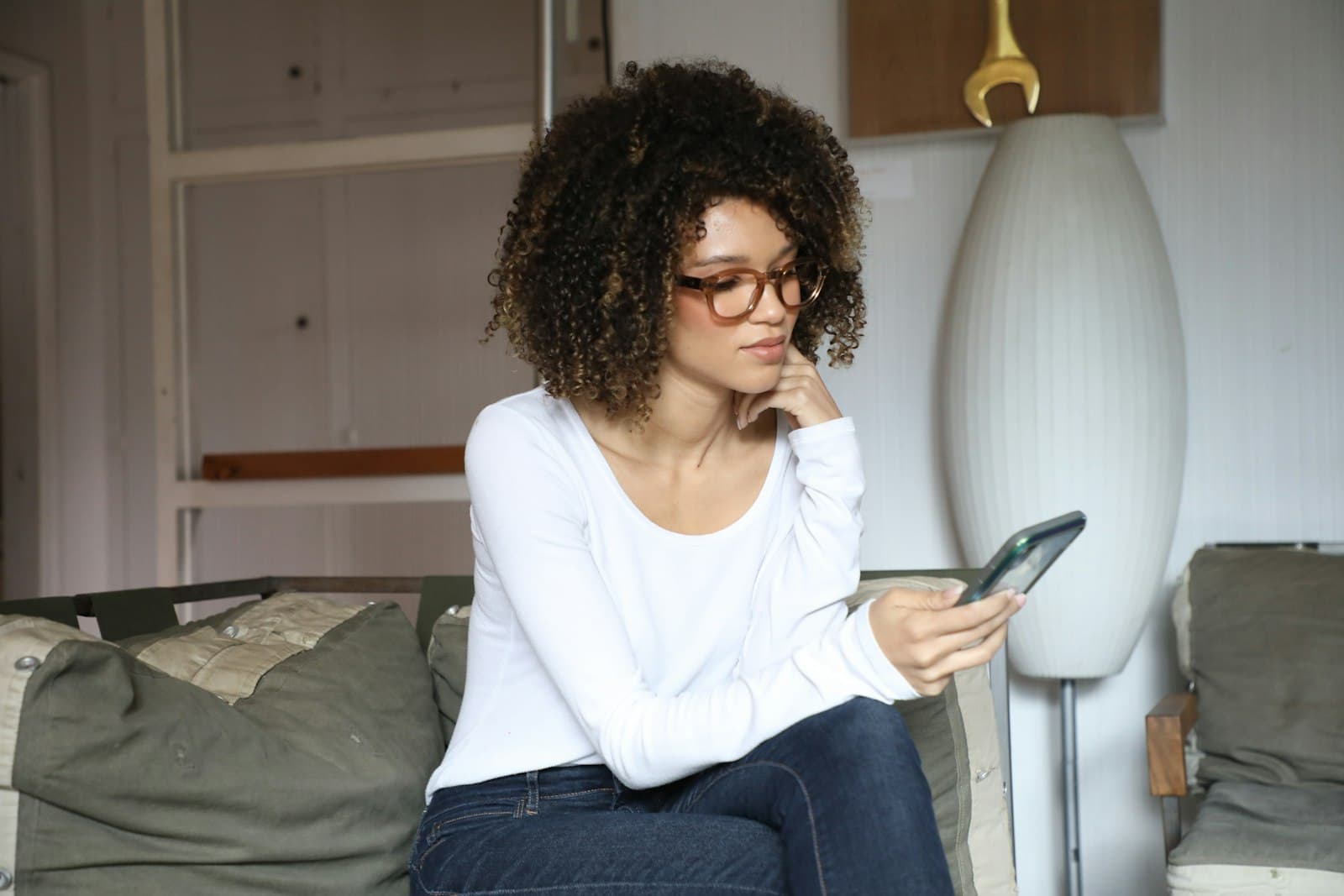 A student sitting on her bed looking at her phone