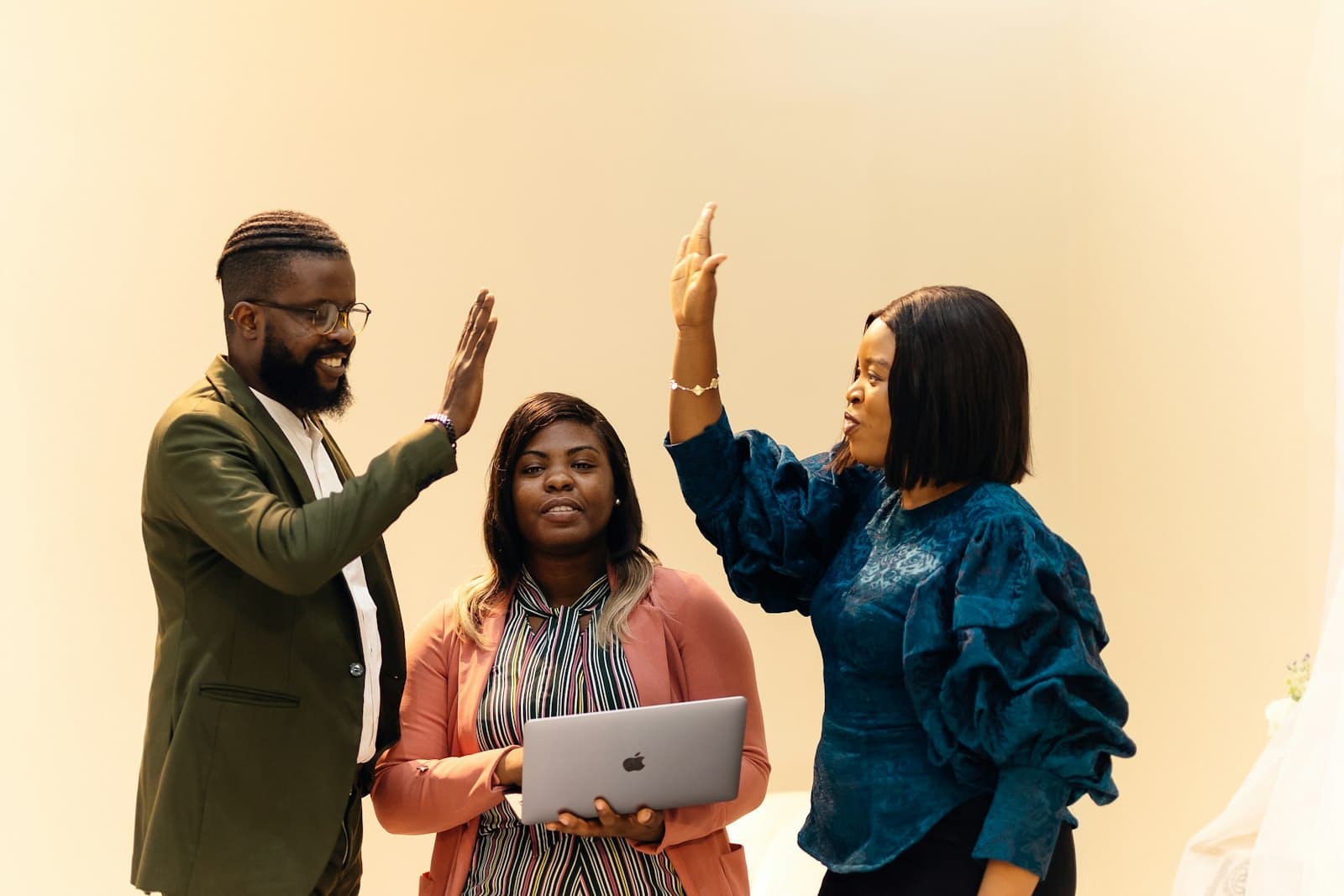 Three colleagues celebrating with a high five in the office